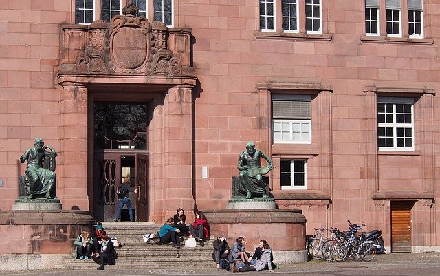 Mehrere Studenten sitzen vor der Universität in Freiburg